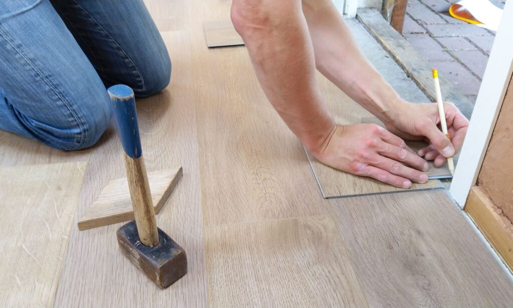creative-approach-img Flooring installer measuring hardwood planks during installation